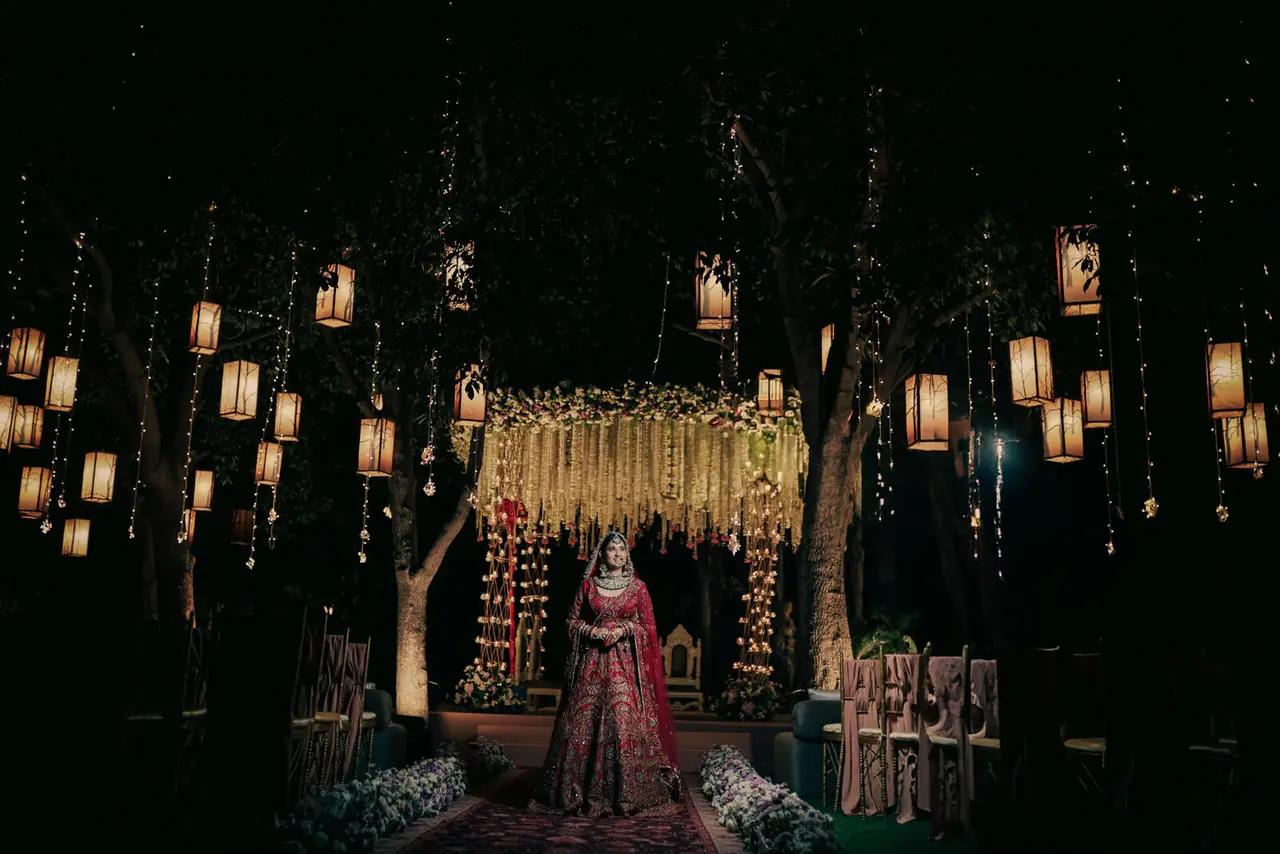 Wedding mandap lit with hanging lanterns at night